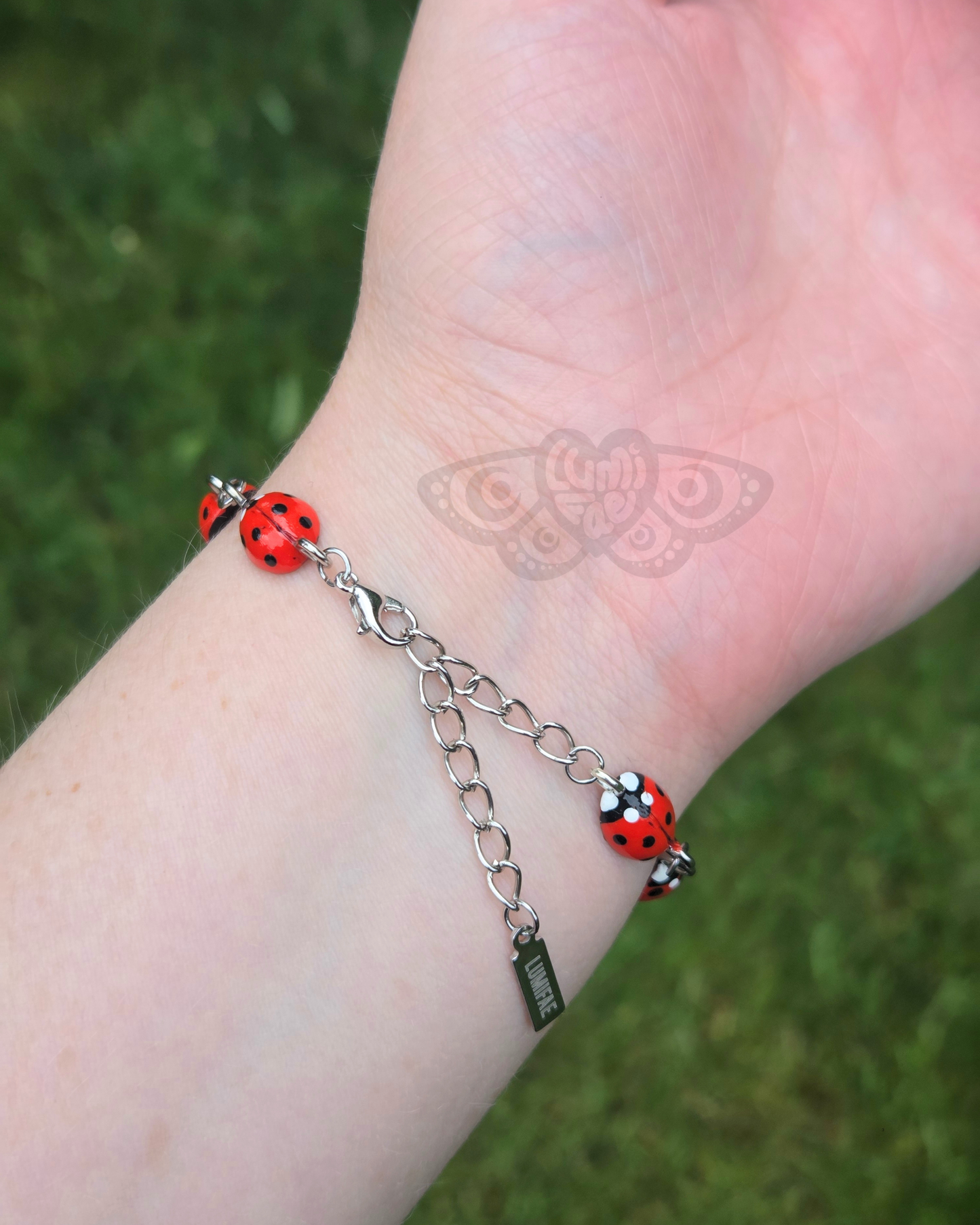 Back of bracelet Bracelet with ladybugs on a wrist against a grassy background