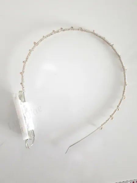 LED Headband with lights turned off laying flat on a white background. The silver headband is wrapped with silver wire and has a thin white battery pack attached to the left side.