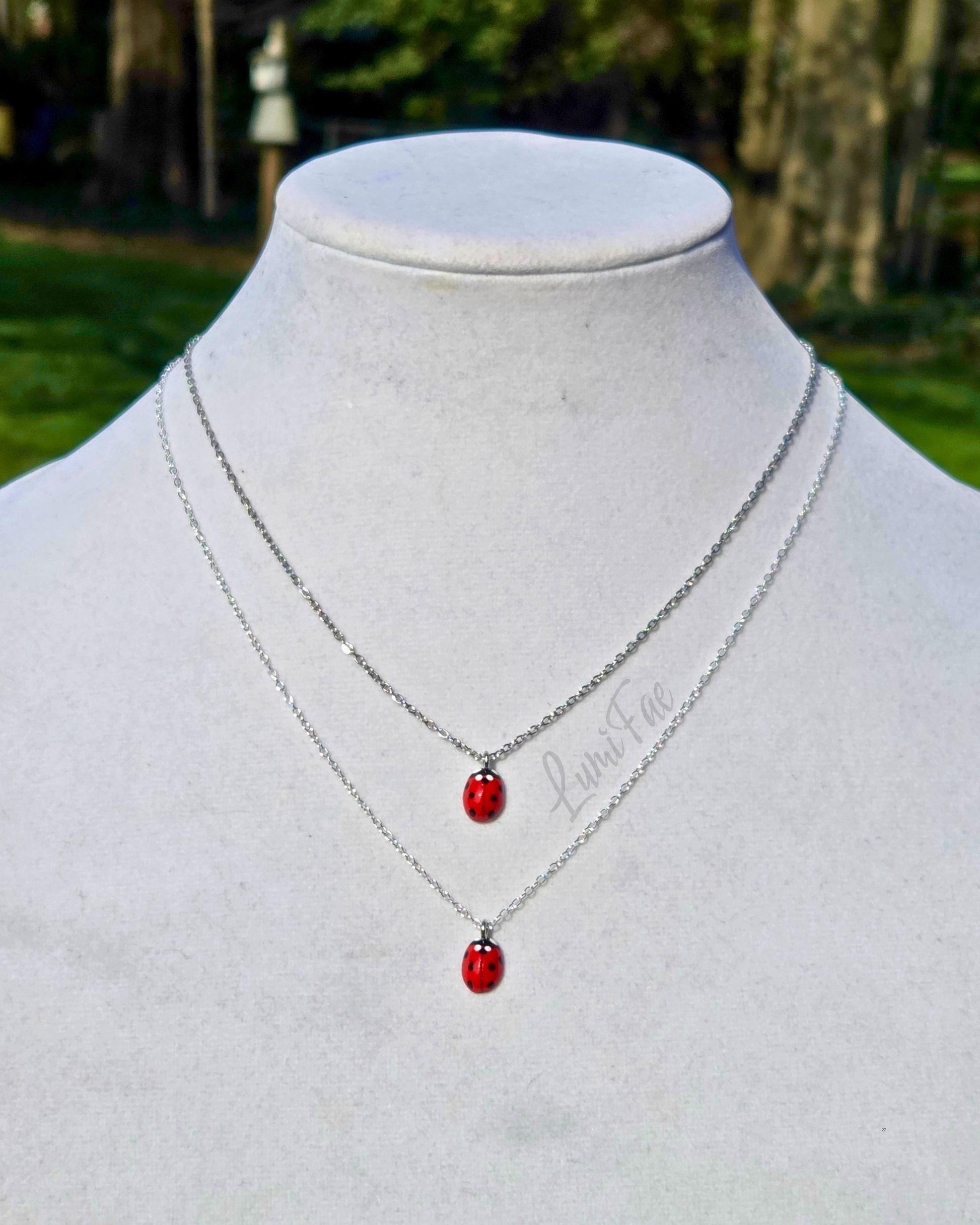 Ladybug necklace on dainty stainless steel chain and ladybug necklace on dainty sterling silver chainboth shown on neck form. First necklace is shorter.