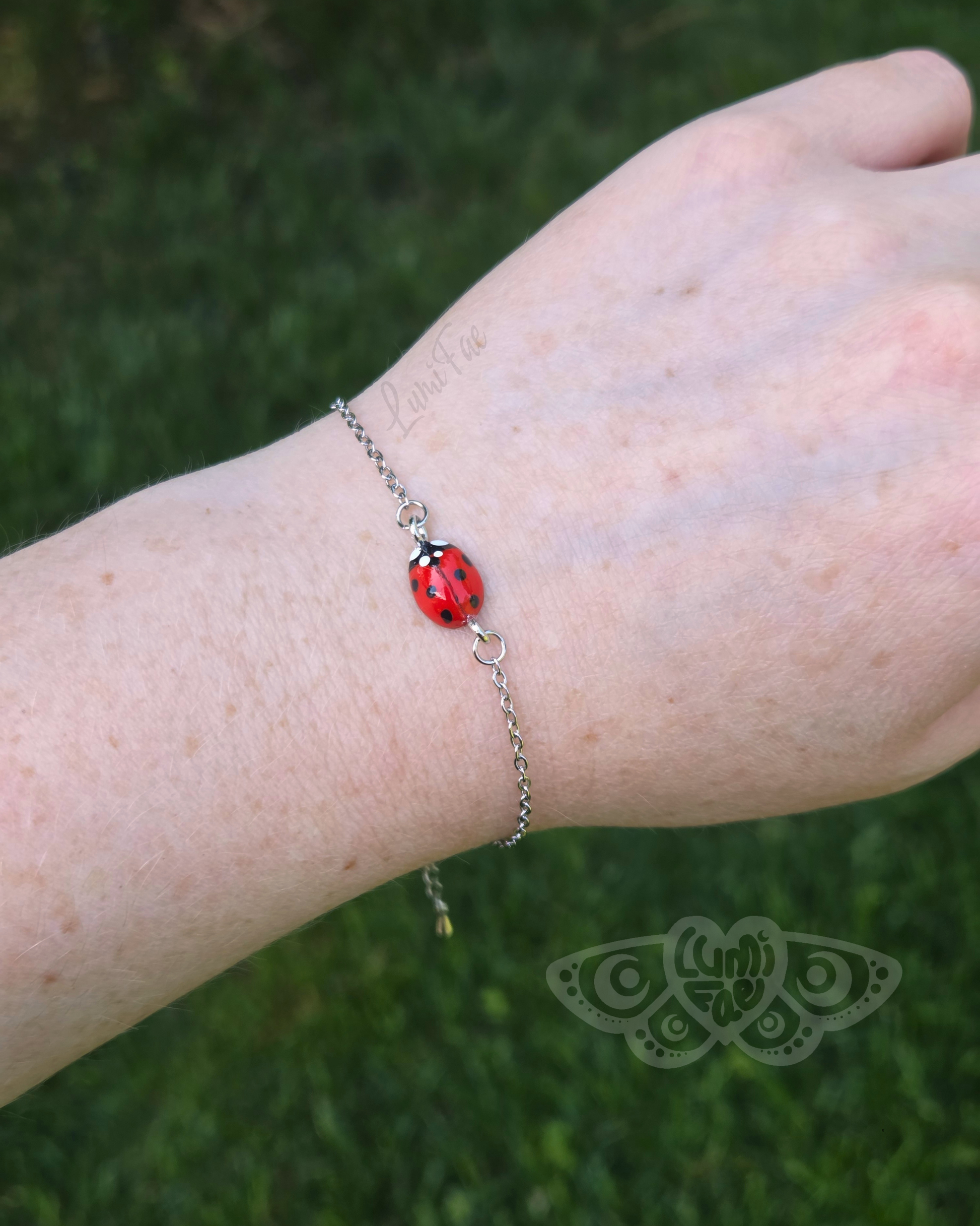 Bracelet featuring a realistic red ladybug worn on a wrist against a grassy background
