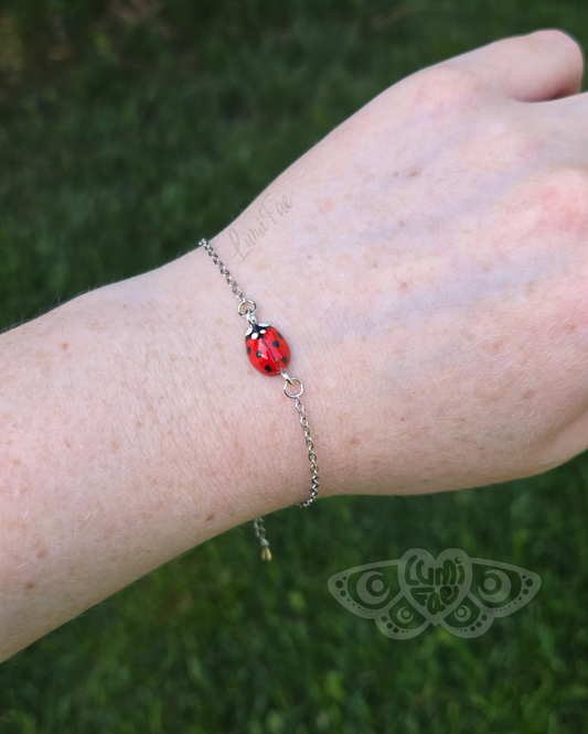 Bracelet featuring a realistic red ladybug worn on a wrist against a grassy background